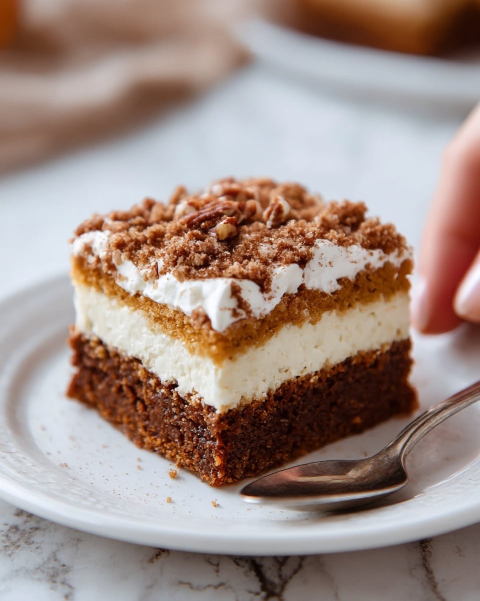 A close-up of a square slice of layered dessert on a white plate with crumbs around it. The bottom layer is a thick, soft brown cake. Above that is a smooth, creamy white layer, followed by a thin light brown layer. The top of the dessert is covered with a thick, fluffy white cream and sprinkled generously with crumbly brown topping. The background is a soft white marbled texture with blurred brown shapes resembling pumpkins. Photo taken with an iphone --ar 4:5 --v 7