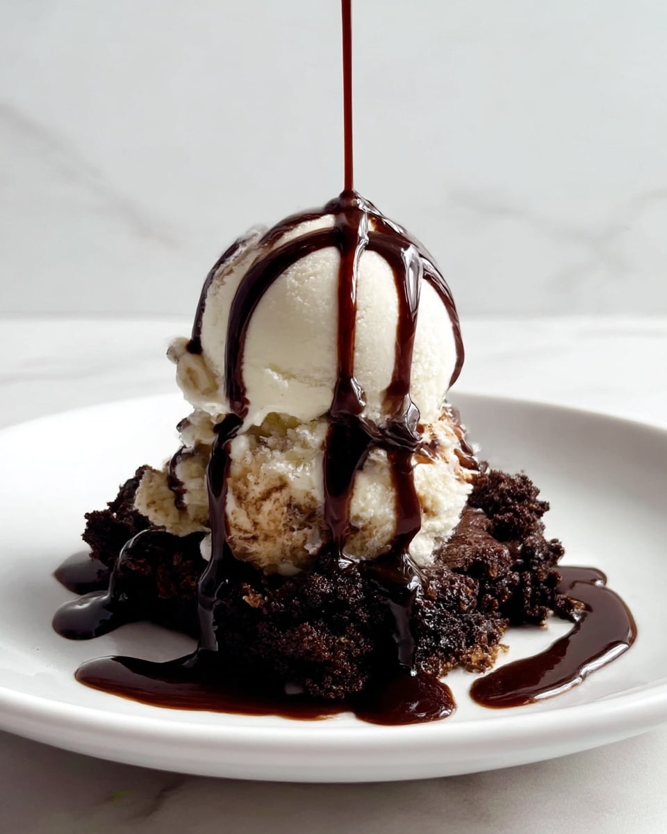 A close-up of a dessert on a white plate set on a white marbled texture. The bottom layer is rough, dark chocolate cake crumbs with a slightly crumbly texture. On top of the crumbs sits a smooth, round scoop of creamy white vanilla ice cream. Dark, glossy chocolate syrup is being poured over the ice cream, drizzling down in thick, flowing lines and pooling slightly on the chocolate cake base, creating a rich contrast between the dark syrup, white ice cream, and dark cake crumbs. photo taken with an iphone --ar 4:5 --v 7