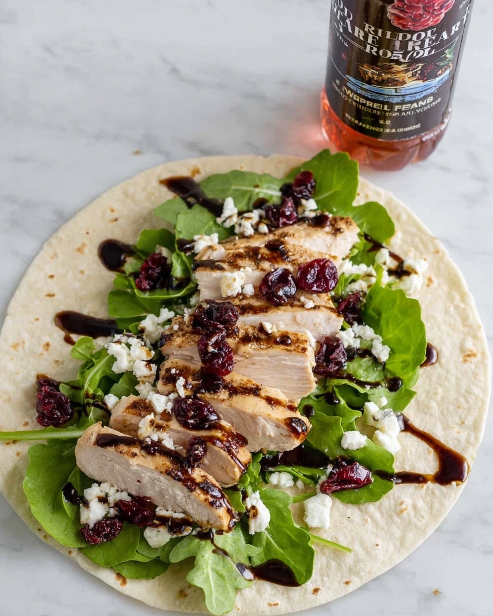 A white tortilla laid flat on a white marbled surface is filled with several layers: at the bottom, fresh green arugula leaves create a bed; on top of the greens are thick slices of grilled chicken breast with visible grill marks and a light brown crust; scattered over the chicken are small white crumbles of cheese and deep red dried cranberries; the entire filling is drizzled with a dark balsamic glaze sauce that adds a glossy texture and contrast. In the background, there is a bottle of raspberry-flavored iced tea. photo taken with an iphone --ar 4:5 --v 7