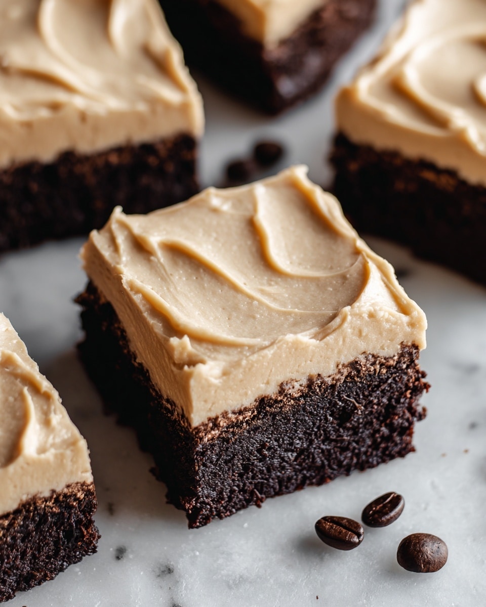 This image shows square-shaped chocolate brownies with two layers placed closely together on a white marbled texture. The bottom layer is thick, dark brown, and dense with a slightly crumbly texture, while the top layer is a smooth, creamy, light tan frosting spread evenly with soft swirls. Around the brownies, there are a few scattered dark brown coffee beans adding contrast to the white marbled surface. The photo is taken from a close-up angle highlighting the fine texture of both layers. photo taken with an iphone --ar 4:5 --v 7