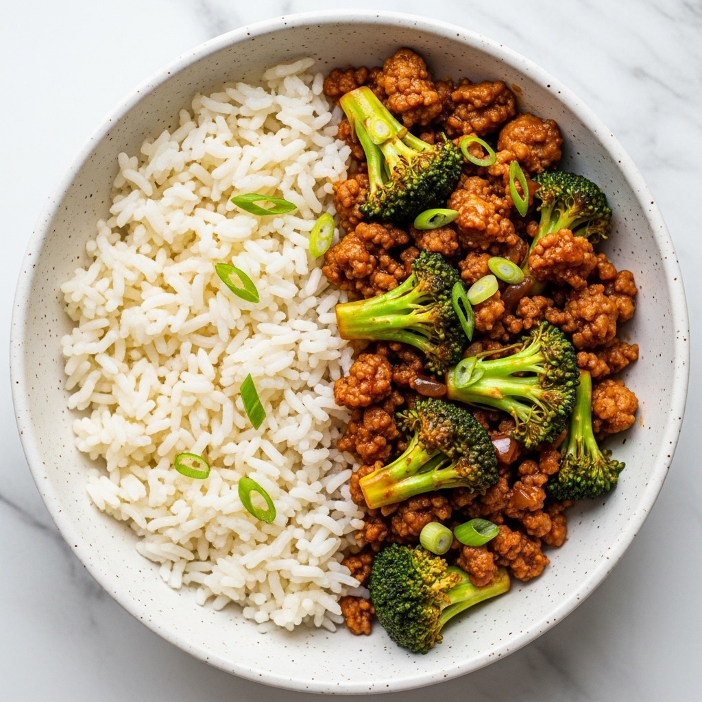 A white speckled bowl holds two layers of food: on one side is a layer of plain, cooked white rice with long grains and a soft texture, and on the other side is a savory stir-fry made of small bits of brown ground meat mixed with bright green broccoli pieces, all coated in a shiny, rich brown sauce with some green onion slices scattered on top. The bowl rests on a surface with a white marbled texture. photo taken with an iphone --ar 4:5 --v 7